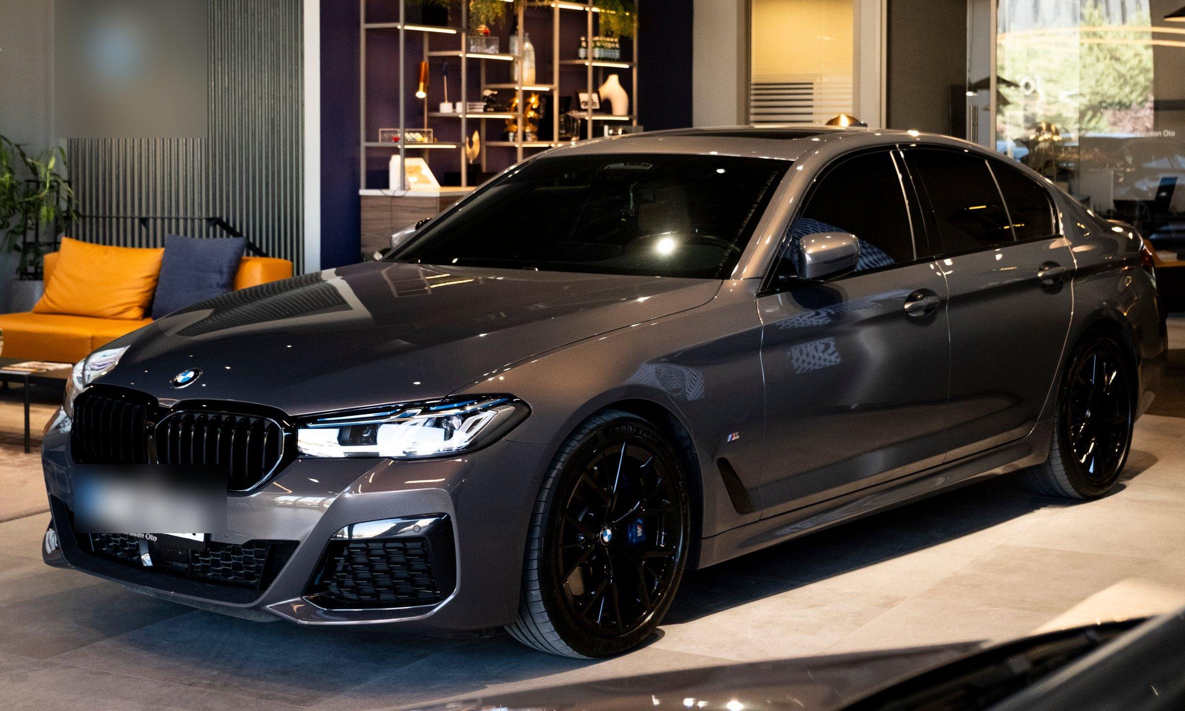 Grijze sedan in driekwart vooraanzicht in een verlichte showroom.